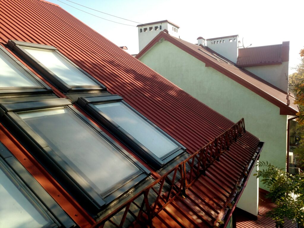 Red tiled house roof with attic windows. Roofing construction, window installation